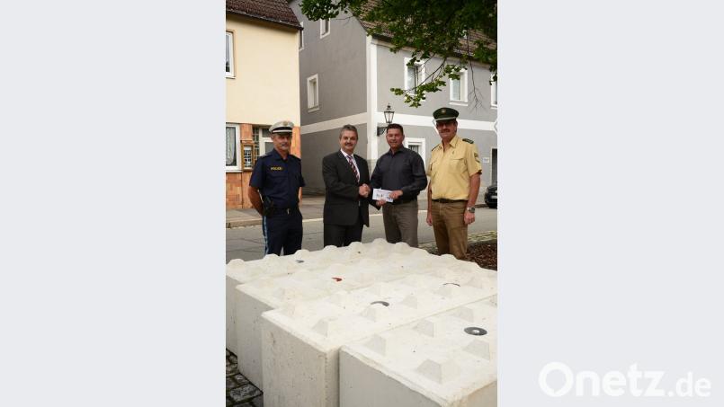 Andreas Wutzlhofer (Zweiter von links) überreichte Rainer Rewitzer 500 Euro als Zuschuss für 14 &quot;Beton-Legosteine&quot;. Erster Polizeihauptkommissar Martin Zehent (rechts) lobte die Initiative als mustergültig. Polizeihauptkommissar Bernhard Dobmayer freute sich ebenfalls über das mit dem Kauf vermittelte Sicherheitsgefühl für die Bürger.	Bild: bey
