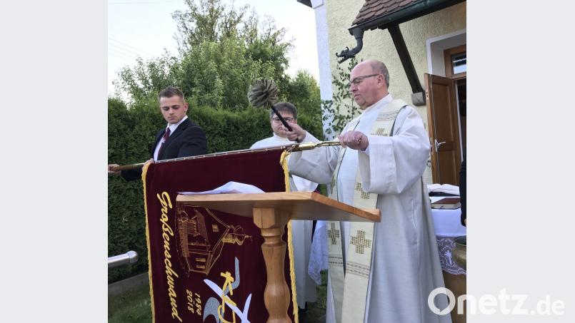 Pfarrer Wilhelm Bauer segnet die neue Fahne der Katholischen Landjugendgruppe Großenschwand. Fahnenträger Rafael Wurzer (links) und Diakon Norbert Hammerl beobachten das Geschehen.  	Bild: eig