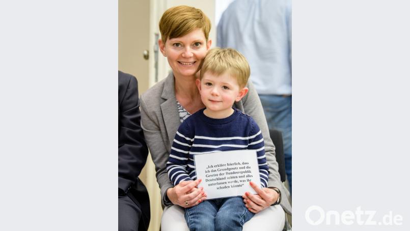 Die neue deutsche Staatsbürgerin Annamaria Varga-Balough, eine in Passau lebende Diplomsozialpädagogin aus Ungarn, hält mit ihrem Sohn Theo einen Zettel mit dem Eid auf die Verfassung.  	Bild: Matthias Balk/dpa