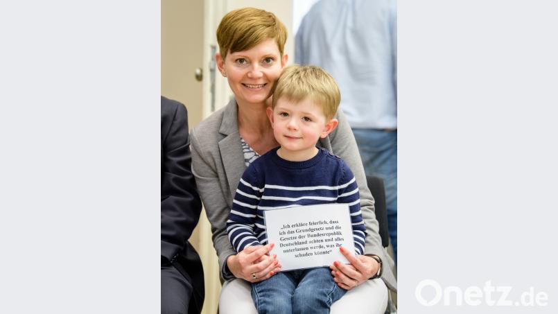 Die neue deutsche Staatsbürgerin Annamaria Varga-Balough, eine in Passau lebende Diplomsozialpädagogin aus Ungarn, hält mit ihrem Sohn Theo einen Zettel mit dem Eid auf die Verfassung.  	Bild: Matthias Balk/dpa Matthias Balk