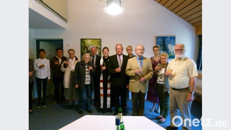 Mit Sekt stoßen Pfarrerin Anne Utz (Sechste von links) sowie die Bürgermeister Peter Lehr (links daneben) und Klaus Lehl (Sechster von rechts) mit Mitgliedern der evangelischen Kirchengemeinde auf die neue Steuerung der Glockenuhr an.  	Bild: rn