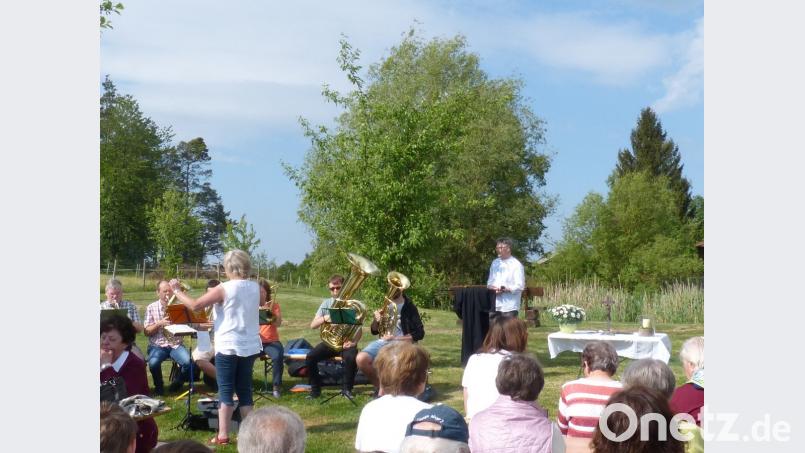 Pfarrer Markus Vedder (im Hintergrund, rechts) und der Posaunenchor gestalten die Andacht im Grünen. Bild: fm