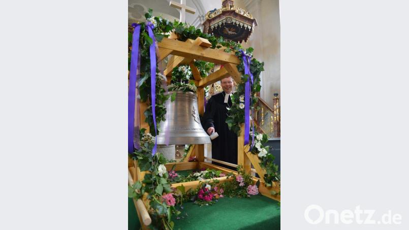 Dekan Wenrich Slenczka schlägt die neue Glocke, die eine Friedenstaube ziert, von Hand an.