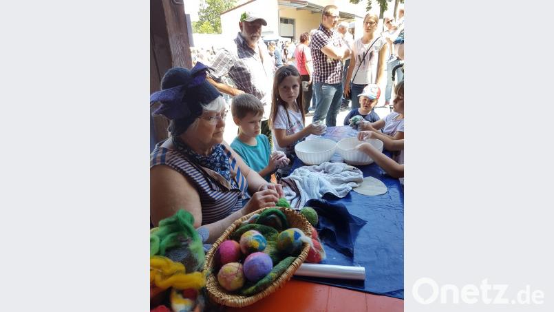 Eine Filzerin zeigt den Kindern, wie aus gefärbter Schafwolle bunte Filzkugeln entstehen. Die neugierigen Kleinen dürfen selbst ausprobieren.