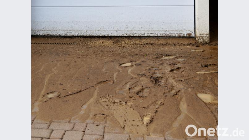 Schlamm auf Gehwegen und vor Garagen blieben zurück als das Wasser abgezogen war. tr