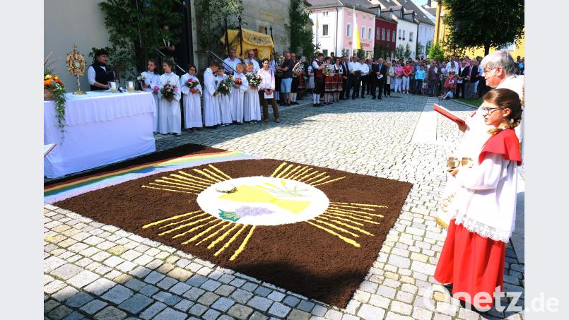 Im Mittelpunkt der feierlichen Fronleichnamsprozession steht die Monstranz mit Hostie als Zeichen der leiblichen Gegenwart Jesu Christi in Brot und Wein. Der farbenprächtige  Motiv-Teppich vor dem vierten Altar auf dem Kirchplatz ist ein Werk des Frauenbundes. do
