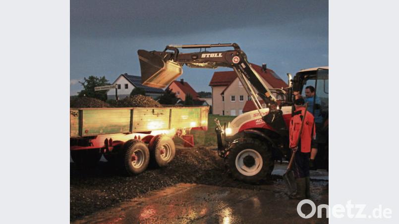 Mit einem Traktor beseitigen Helfer in der Pfarrer-Schuhmann-Straße in Konnersreuth auf die Fahrbahn gespülten Schotter. kro