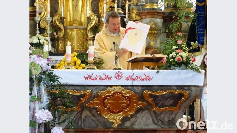 Pfarrer Waleszczuk hat das neue Gewand angezogen, in der Hand eine dazu passende Karte, mit der Überschrift &quot;Möge die Liebe Gottes Sie stets begleiten&quot; twg