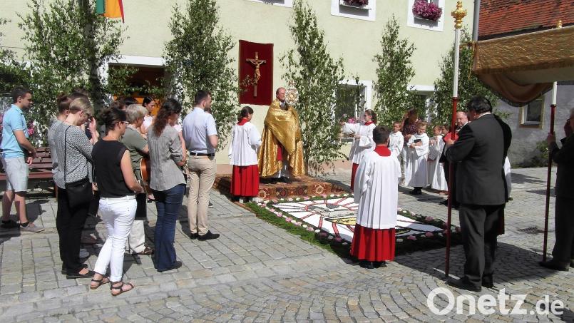 An jeden der drei Altäre segnet Pfarrer Heribert Stretz (hinten) die Gläubigen mit der Monstranz. Die jeweiligen Blumenteppiche legen Frauen aus Köglitz. hl