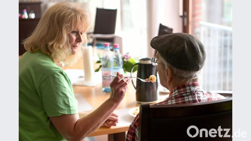 Eine Pflegerin betreut einen älteren Mann während des Frühstücks in einem Seniorenpflegeheim. Holger Hollemann/dpa