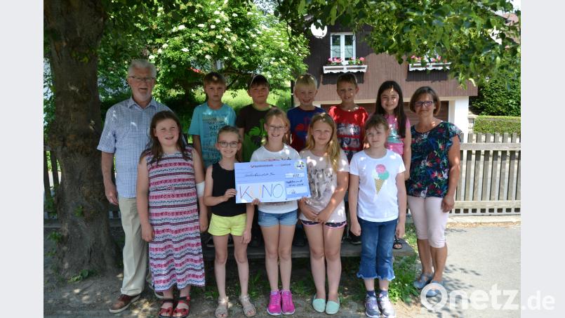 Die zehn Kommunionkinder übergeben 1200 Euro an Dr. Hans Brockard (links) von der KUNO und Irene Fischer (rechts) vom Förderverein Rasselbande. plym