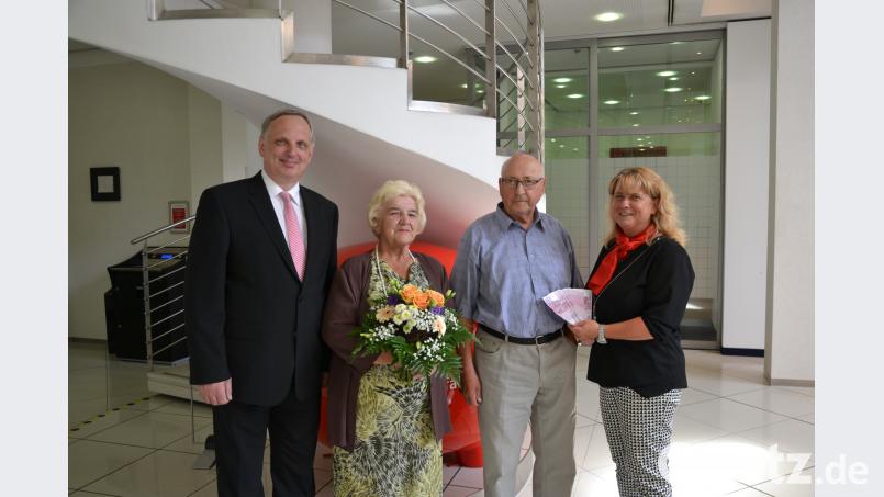 Filialbereichsleiter Peter Hamm (links) und Kundenbetreuerin Manuela Müller (rechts) überreichen an Annemarie und Werner Maier den Geldgewinn und einen Blumenstrauß. plym