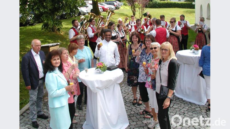 Das besondere Patrozinium zum 80jährigen Bestehen der Pfarrkirche feiern die Gläubigen auf dem Kirchplatz. Dort stoßen auch Pater Joy (Mitte) und Gemeindereferentin Gabi Sieder (Vierte von rechts)  auf das freudige Ereignis an. ld