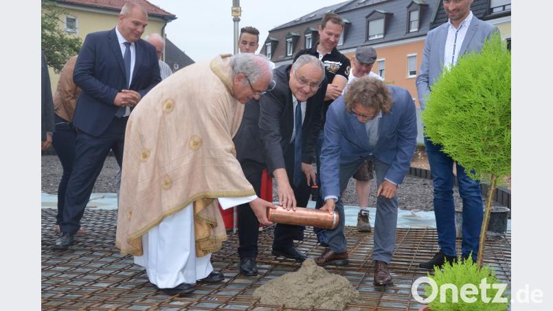 Stadtpfarrer Gerhard Pausch, Bürgermeister Lothar Höher und Architekt Manfred Schwemmer legen die Zeitkapsel ins Fundament des neuen Pfarrheims. Kunz