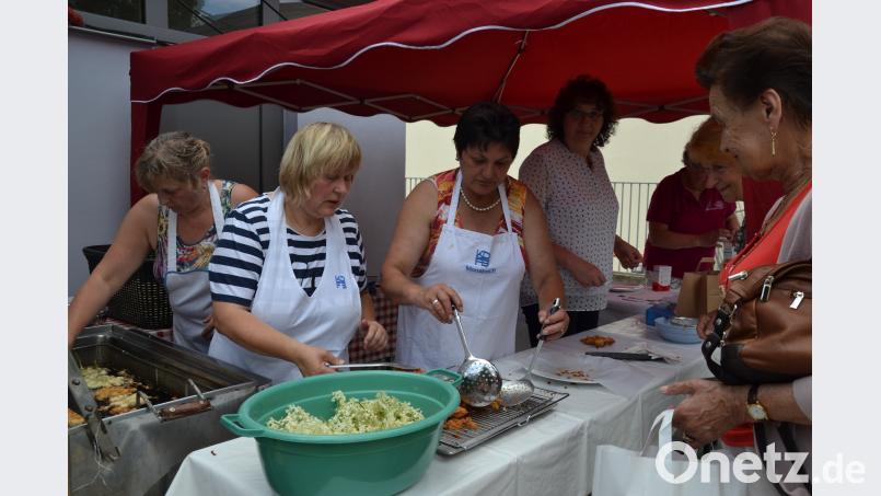 Mitglieder des Frauenbunds Moosbach servieren beim Holunderfest im Garten am Pfarrheim frische knusprige „Hollerküchln“,  Hollerwasser, -sekt, Hugo und vieles mehr aus dem „Gesundheitsbrunnen Holunder“. Die Hollerküchl-Bäckerinnen und Helferinnen haben alle Hände voll zu tun. gi