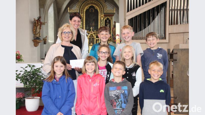 Vorsitzende Petra Waldhauser (Mitte links) und eine betroffene Mutter (hinten links) danken den Gebenbacher Erstkommunionkindern für die Spende zugunsten der Selbsthilfegruppe krebskranker Kinder swo