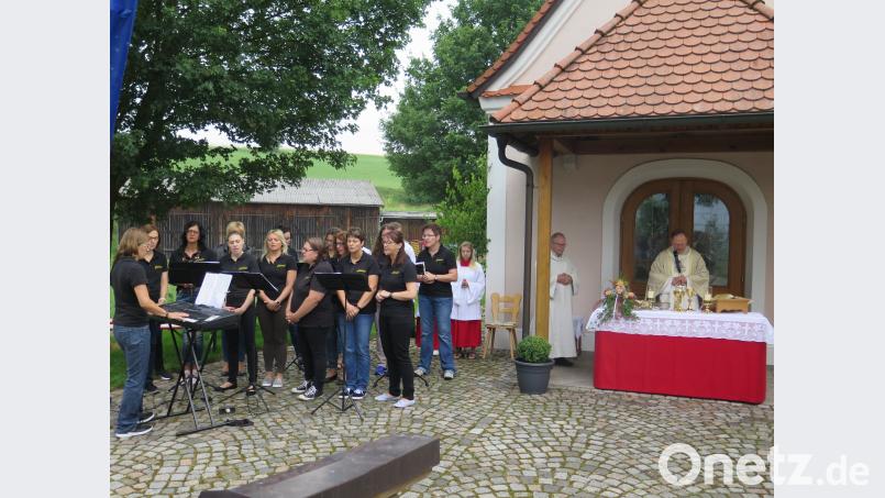 Der Chor „Laudate“ (links) gestaltet mit Liedern den Festgottesdienst, den Pfarrer Heribert Stretz (Mitte) vor der Kapelle zelebriert. jzk