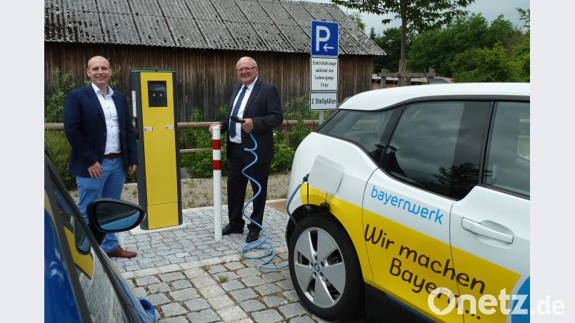 Bürgermeister Heinz Weigl (rechts) steckt das Ladekabel an der neuen Ladesäule am Parkplatz "Hütgraben" an. EON-Kommunalbetreuer Daniel Pangerl erklärt wie die Stromtankstelle funktioniert. Portner