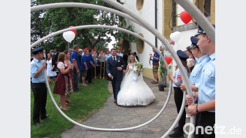 Lara und Oliver Pöhnl durchschreiten nach der kirchlichen Trauung ein langes Spalier. sei