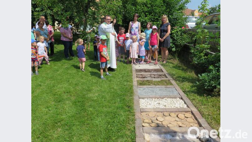 Vor den beiden Gruppenleiterin Renate Pressler und Simone Beck (von rechts), den Kindern und Eltern segnet Stadtpfarrer Konrad Amschl den Barfußpfad. Zaglmann, Josef [JZK] (zaglmann@t-online.de)