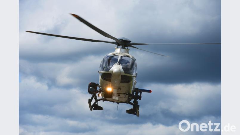 Mit einem Helikopter samt Suchscheinwerfer fliegt die Polizei den Wald am Bergmühlweg ab. Bayerische Polizei