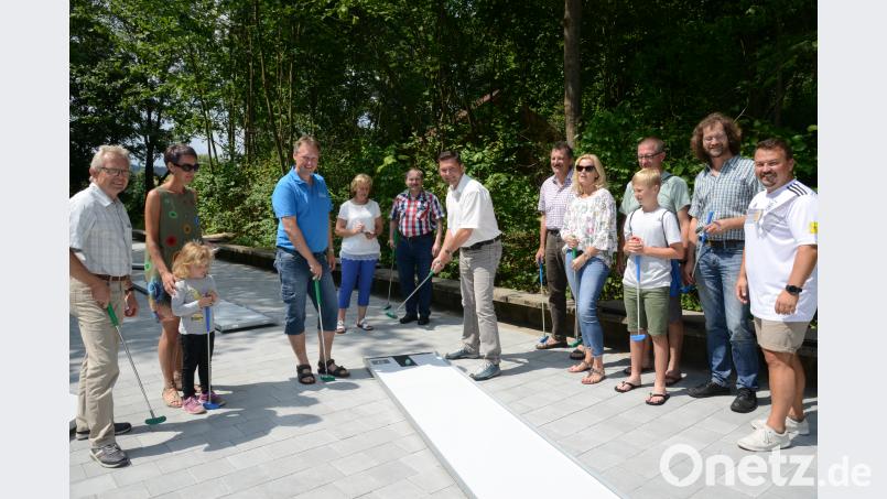 Stefan Kabitschke (Dritter von links), Vorsitzender des Freibadfördervereins, und Bürgermeister Rainer Rewitzer (Sechster von links) führen die ersten Schläge auf der neuen Minigolfanlage im Freibad aus. bey