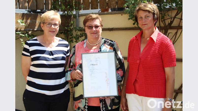 Vorsitzende Lydia Graf (rechts) und ihre Stellvertreterin Anne Wendl (links) überreichen der neuen Ehrenvorsitzenden Maria Hirsch die Urkunde. exb