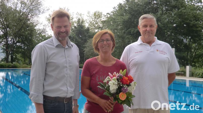 Bürgermeister Alwin Märkl (links) und Schwimmmeister Uwe Paul (rechts) begrüßen Anita Butz als ersten Badegast. gef
