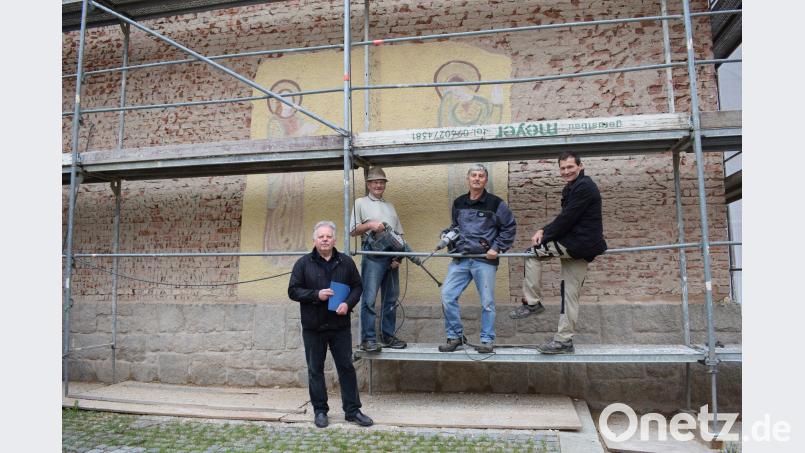 Auch das Heiligenbild im Putz (Hintergrund)  muss für die Außensanierung der Kirche St. Matthäus weichen. Alfons Vollath und Alfons Franz  sind zwei von 15 Helfern, die beim Abschlagen des Außenputzes mithelfen. szl