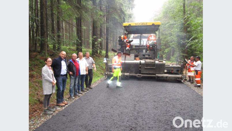Aufmerksam verfolgen Anna-Lena Grötsch, Bauingenieur Bamler GmbH Vohenstrauß, Bürgermeister Max Völkl , Bauingenieur Dietmar Hammerl, Stefan Haupt von der Frima Hartinger und Firmenchef Josef Hartinger (von links) das Aufbringen der ersten Asphaltschicht. es