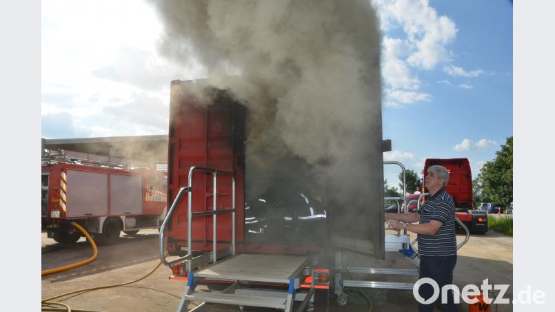 Die Feuerwehrleute erleben im Brandcontainer des Landesfeuerwehrverbands wie sich ein Feuer blitzschnell entwickelt. Albert Burger öffnet die Tür des Brandcontainers wieder und der schwarze Qualm steigt in den blauen Abendhimmel. dob