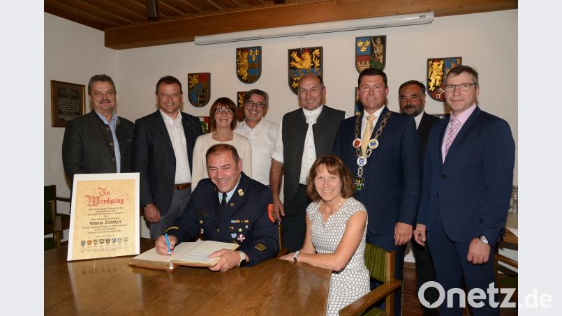 Die Bürgermeister Andreas Wutzlhofer, Anton Kappl, Margit Kirzinger, Reiner Gäbl, Max Völkl, Rainer Rewitzer, Josef Beimler und Hermann Ach (stehend, von links) danken Ehrenkreisbrandinspektor Johann Rewitzer für die herausragende Zusammenarbeit. Rewitzer trägt sich beim Festakt als erster ins Goldene Buch der Stadt Pleystein ein. Ehefrau Resi war in den 31 Jahren der Tätigkeit Rewitzers der große Rückhalt. bey