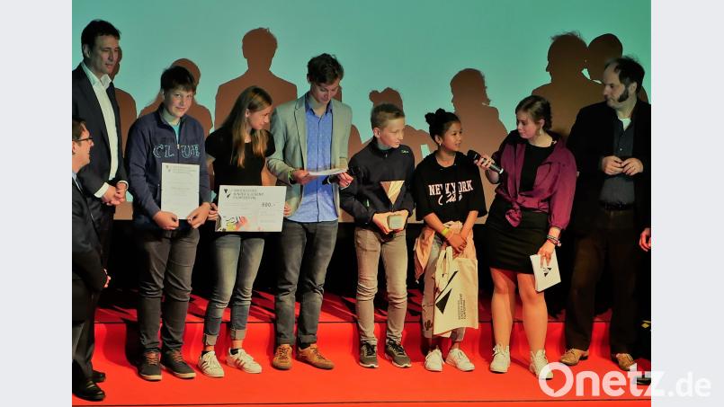 Staatsminister Georg Eisenreich (links) und der „Spurensicherer vom Franken-Tatort“ Matthias Egersdörfer (rechts) überreichten Lukas, Marie, Vincent und Patsita  der Abordnung der AG Video von der Grundschule Rieden Trophäe, Urkunde und Scheck für ihren Film „Schlank“. Egid Spieß