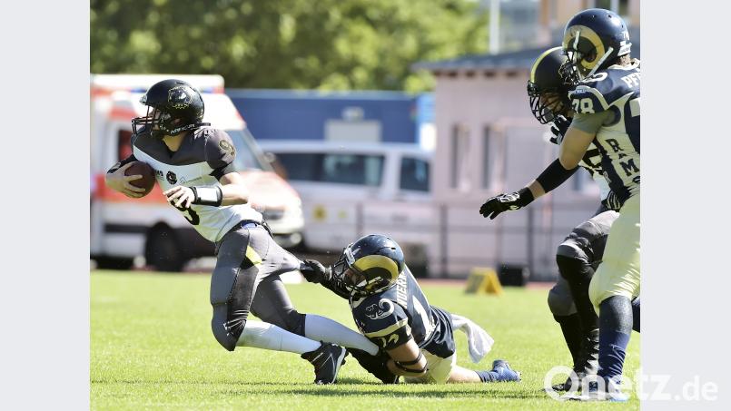 Mit der einen Hand umklammert der Nürnberger das Schienbein von Christopher Wells (links), mit der anderen zerrt er an der Hose des Amberger Quarterbacks. Die überstand den Zupf-Test bei dieser Aktion nicht, aufhalten ließen sich die Mad Bulldogs aber auch von Löchern in der Hose nicht... Ziegler