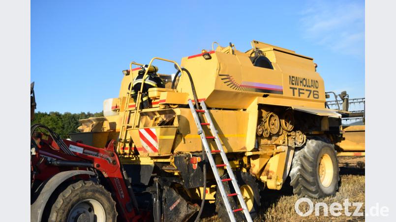 Während die Atemschutzträger den Mähdrescher nach Glutnestern absuchen platziert ein Landwirt seine Frontladerschaufel unter dem Kraftstofftank, um den auslaufenden Diesel aufzufangen. Jürgen Masching