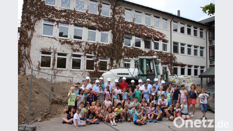 Im Hintergrund der sanierungsbedürftige A-Bau der Schule, vorne Erwachsene, die für den Umbau verantwortlich sind, und Grundschüler, die in den Genuss der Modernisierung kommen werden. Thomas Dobler