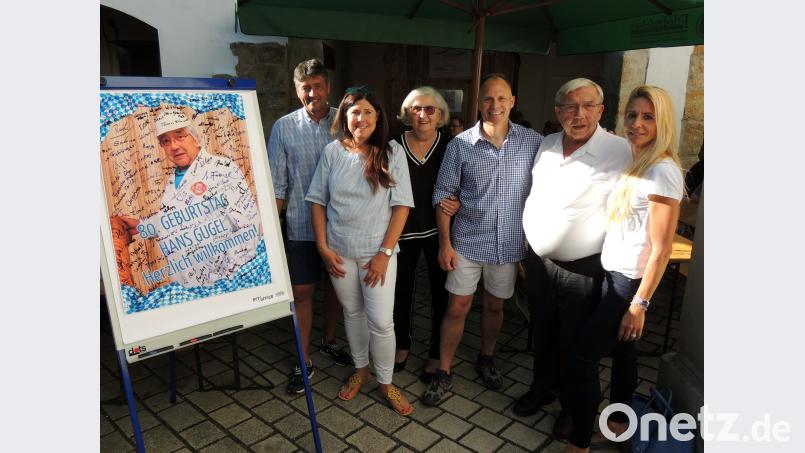 Mit dem Plakat eines „Metzgermeisters in Action“ heißt die Belegschaft die Gäste zur Geburtstagsfeier von Hans Gugel (Zweiter von rechts) willkommen. Zum 80. gratulieren unter anderem (von links) Bürgermeister Edgar Knobloch, Tochter Beatrix, Ehefrau Helga, General LaNeve und Tochter Hannelore.  mor