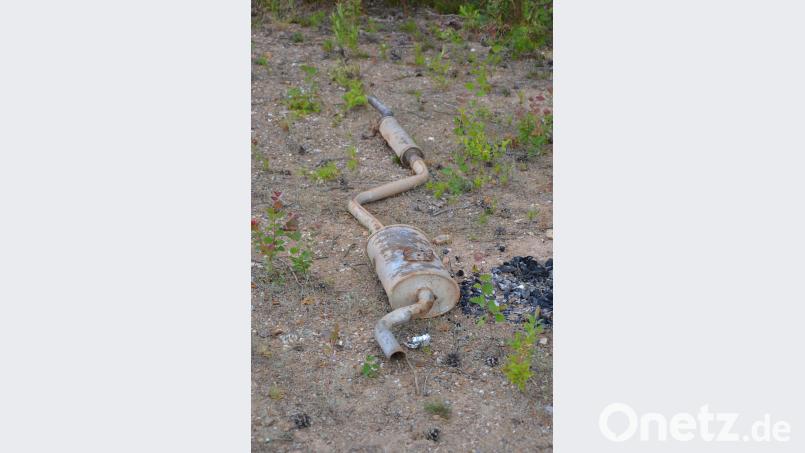 Ein verrosteter Auspuff liegt mitten in der Natur. spi