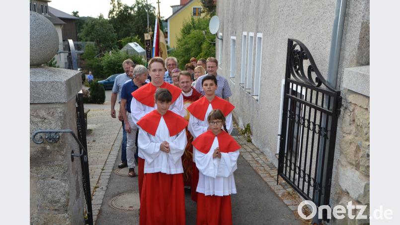 Mit den Fahnenabordnungen ziehen die Ministranten mit Dekan Alexander Hösl über das Friedhofsportal zur St.-Thomas-Kirche, um das Patrozinium zu feiern. dob