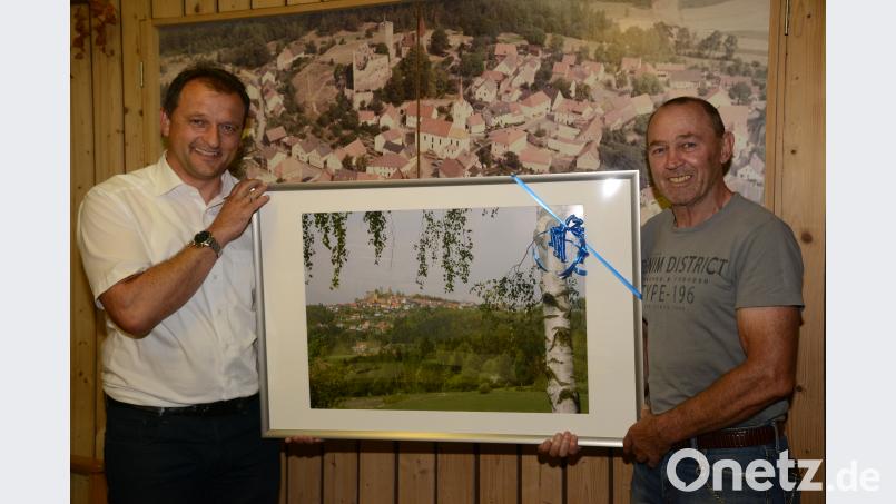 Bürgermeister Anton Kappl (links) überreicht Hermann Gebhardt anlässlich seines Ausscheidens aus dem Marktgemeinderat Leuchtenberg ein Bild mit der Ansicht des Ortes. bey