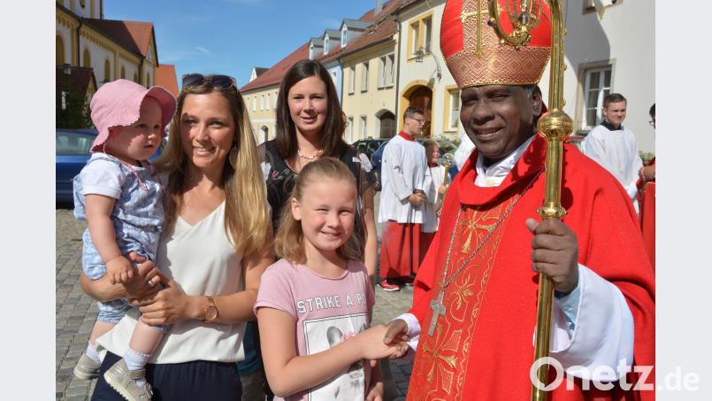 Bischof Moses begrüßt vor dem Pfarrhof zahlreiche Eltern mit ihren Kindern und spendet den Segen. jr