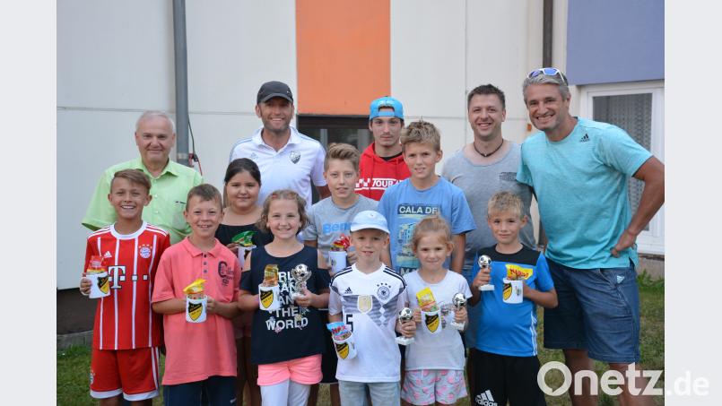 Mit Schmackes dreschen die Kinder den Ball in die Maschen. Für die schnellsten Torschüsse gibt es von Organisator Christian Griener (hinten, Zweiter von links) und Ehrenmitglied Gerd Schönfelder (rechts) SV-Tassen und Süßigkeiten. Von Bürgermeister Günter Kopp kommen noch Gratulationen dazu. ak