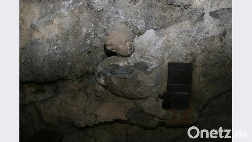 Der steinerne Engel im Inneren der Grotte hält einen Weihwasserkessel in der Hand. Mit beiden Augen „bewacht“ er fest den Opferstock. wro