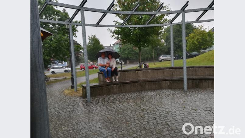 Ein einsames Pärchen unter dem Regenschirm bei Gewitterregen im Stadtpark. dob