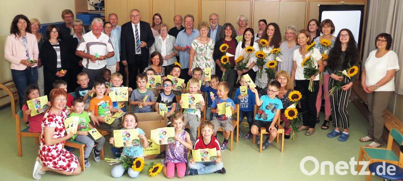 Die schulvorbereitende Einrichtung mit Leiterin Ulrike Grajer (Sechste von rechts) feiert 25-jähriges Bestehen. Die Kinder halten den neuen Flyer. Sonnenblumen gibt es für langjährige Mitarbeiter. Dobmeier