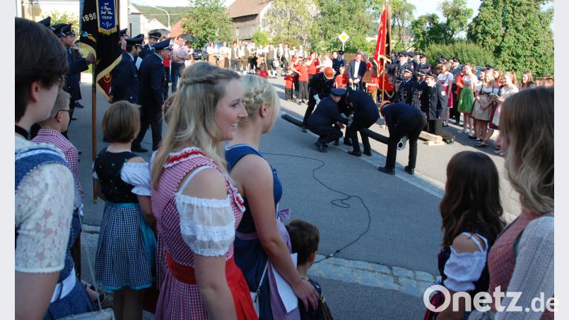 Die Kührieder Festdamen (im Vordergrund) beobachten, wie die Zeinrieder mit verbundenen Augen eine Saugleitung kuppeln. Portner