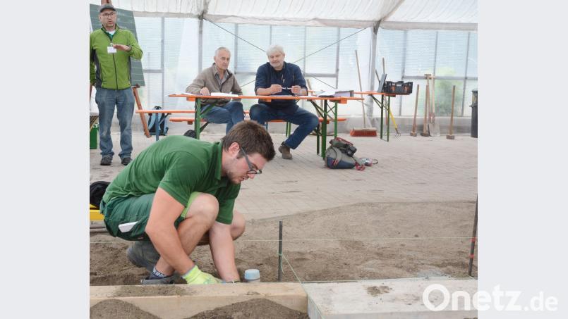 Ein Absolvent werkelt vor den Augen der Prüfer in der Stadtgärtnerei beim praktischen Teil der Abschlussprüfung im Garten- und Landschaftsbau. gsb