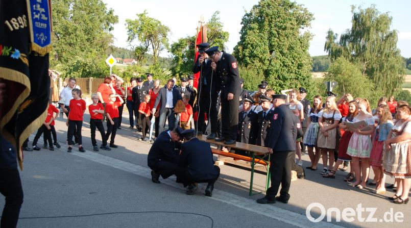 Schirmherr Norbert Eckl (links) und die Jubelwehr Zeinried (kniend die Vorsitzenden und Kommandanten) mit ihren Festdamen beobachteten, wie vier Kameraden einen Bierkrug mittels dünnem Plastikschlauch leeren. Portner