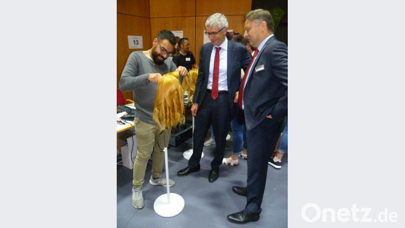 Salim Abo Harash, der 2015 als junger Flüchtling in Amberg landete, erläuterte als Friseur-Azubi IHK-Vizepräsident Dr. Rolf Pfeiffer (Mitte) und IHK-Geschäftsführer Bernhard Reif einige bereits erlernte Fertigkeiten. (usc)