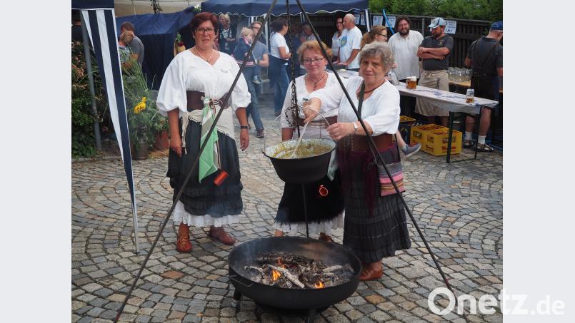 Die Marketenderinnen schöpfen Kartoffelsuppe aus dem Kessel über dem offenen Feuer. krb